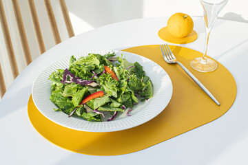 Salad with yellow leather table mat on white table.	
