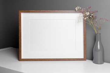Landscape wooden frame mockup for artwork, photo and print presentation with dry flowers over grey...