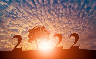 2022 text with tree on green grass field over sunset sky, Happy new year