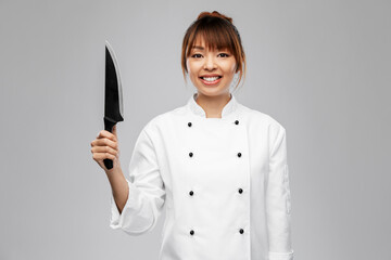 cooking, culinary and people concept - happy smiling female chef with kitchen knife over grey...