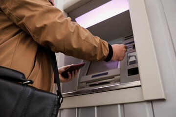 Obraz premium Young man using cash machine for money withdrawal outdoors, closeup