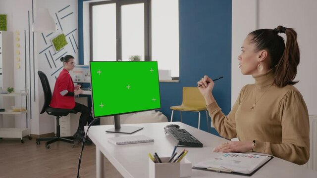 Business women using computer with green screen at desk. Team of people talking while they work with mock up background and isolated template on computer display. Chroma-key copy space