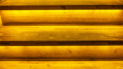 Yellow led light pouring from below onto a wooden staircase. Space for text. Abstract background.