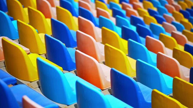 Multi-colored chairs in the stadium. Rows of empty plastic seats in the arena