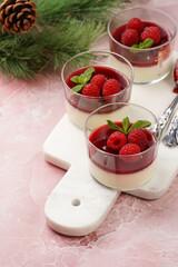 Italian dairy dessert panna cotta with raspberry jam and fresh raspberries on marble board on pink surface, negative space