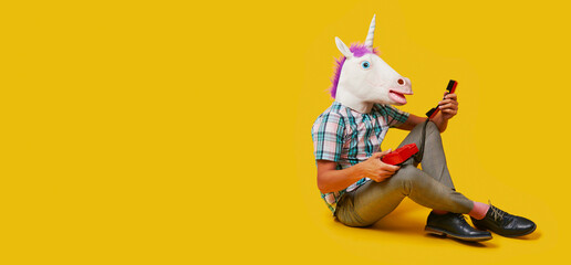 man with a unicorn mask using a phone, web banner