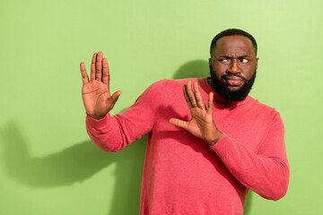 Photo of unsatisfied person arms palms reject empty space sullen face isolated on green color...