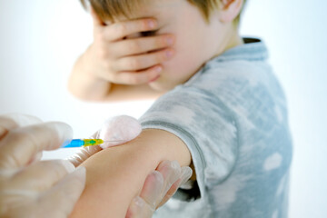Obraz na płótnie Canvas close-up hand of child, syringe in hands of doctor, nurse in gloves makes injection to boy 8-10 years old, medical concept, vaccination against coronavirus covid-19 virus