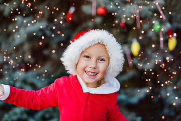 Christmas in july. Child waiting for Christmas in wood in summer. portrait of little girl in red dress decorating christmas tree. winter holidays and people concept. Merry Christmas and Happy Holidays