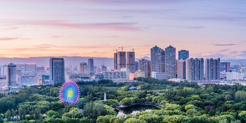 Dusk scenery of Ferris wheel and city skyline in Qingcheng Park, Hohhot, Inner Mongolia, China © Govan