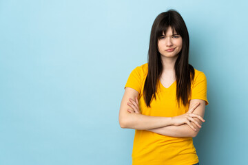Teenager Ukrainian girl isolated on blue background feeling upset