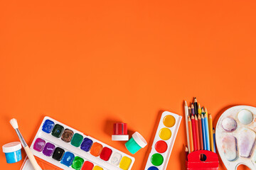 Objects for drawing paints, watercolors and stationery on an orange background. Place for text, school theme