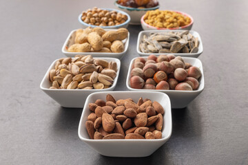 Almond in selective focus. Dried mulberry, hazelnut, pistachio, grape, pistachio, yellow chickpea and sunflower seeds in the background.