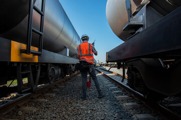 worker on the railway. engineer checking tank for transportation on rail system. Engineer under...