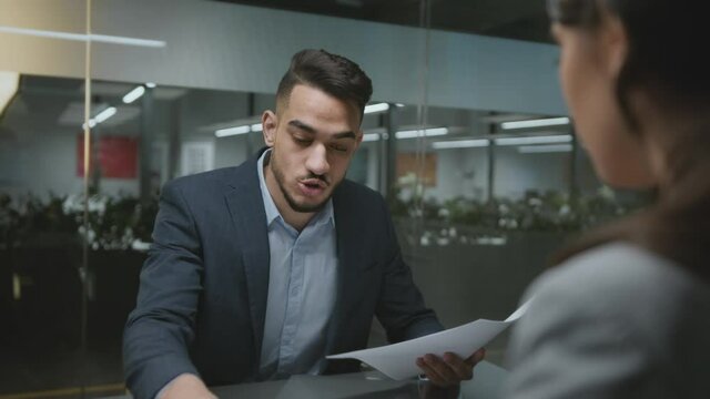 Sexism at workplace. Young angry middle eastern foreman shouting at upset woman employee at office, tracking shot