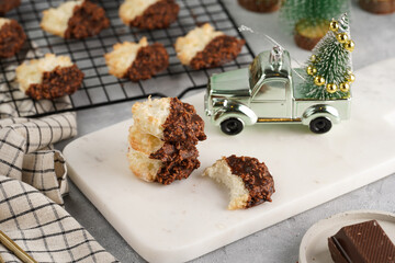 Several coconut flakes cookies dipped in chocolate on a white marble board and baking rack, christmas decoration