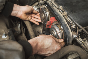 A person independently changes the timing belt in a passenger car - obrazy, fototapety, plakaty