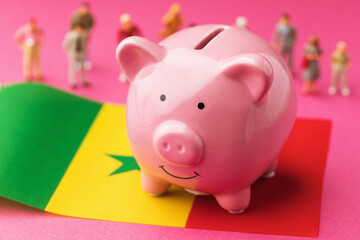 Piggy bank, Senegalese flag and plastic toy men on a colored background, concept on the theme of incomes of the population of Senegal