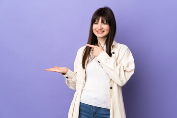 Young Ukrainian woman isolated on purple background holding copyspace imaginary on the palm to...
