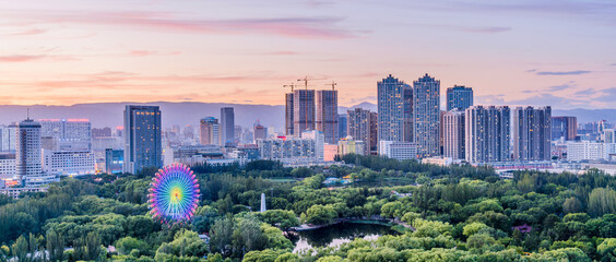 Dusk scenery of Ferris wheel and city skyline in Qingcheng Park, Hohhot, Inner Mongolia, China