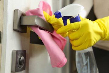 The woman washes and disinfects the doorknob. prevention of the spread viruses.