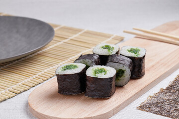 a portion of rolls on a stand, japanese food, sushi on the table, chinese chopsticks, light background