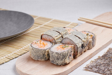 a portion of rolls on a stand, japanese food, sushi on the table, chinese chopsticks, light background