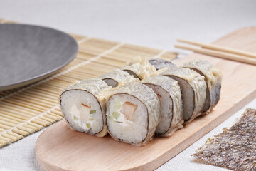 a portion of rolls on a stand, japanese food, sushi on the table, chinese chopsticks, light background