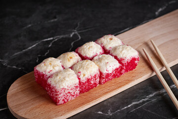 a portion of rolls on a stand, japanese food, sushi on the table, chinese chopsticks, dark background