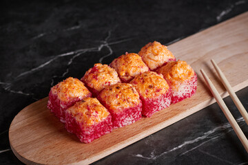 a portion of rolls on a stand, japanese food, sushi on the table, chinese chopsticks, dark background