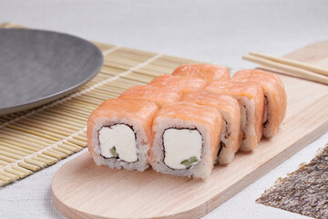 a portion of rolls on a stand, japanese food, sushi on the table, chinese chopsticks, light background