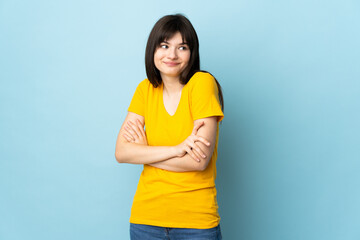 Teenager Ukrainian girl isolated on blue background making doubts gesture while lifting the shoulders