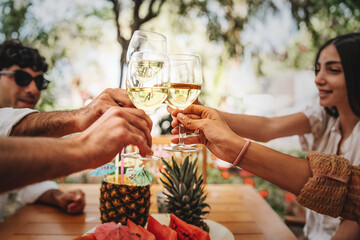 Happy friends toasting white wine outdoors -