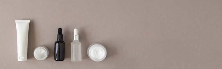 Hand, eye and facial moisturizer cream, serum and essential in glass bottles on beige background....