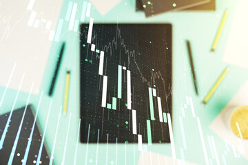 Multi exposure of abstract financial graph and modern digital tablet on desktop on background, top view, financial and trading concept
