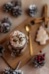 Sweet and tasty chocolate milkshake ice latte in a glass mug on a wooden board with a spoon a cookie and cinnamon