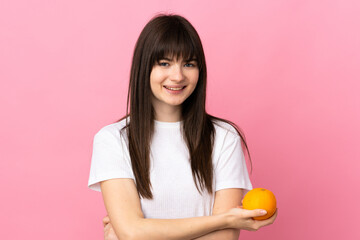 Young Ukrainian woman isolated on pink background holding an orange