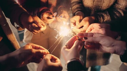 Multi-cultural group of adult friends lighting sparklers and dancing on a rooftop with the city behind them. - Powered by Adobe