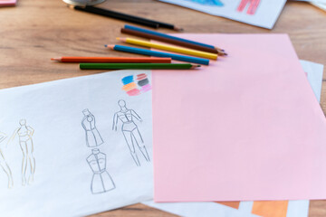 Designer's desk with scattered sketches, paints, liners, pencils. Top view of the messy table of fashion designer. Creative profession concept