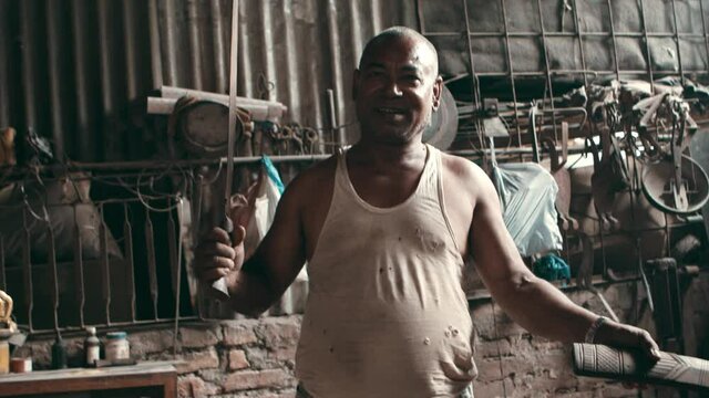Man pulls out large knife from a knife sheath in workshop