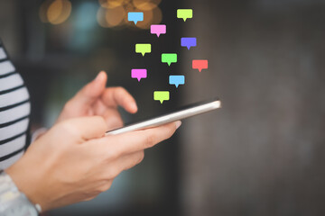 Woman hand using smart phone with chat icon graphic at coffee shop abstract background. Technology business and freelance concept.