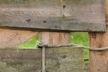 A close-up of a wooden fence closed with a rope
