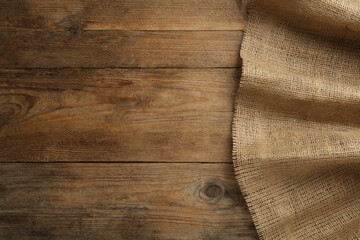 Natural burlap fabric on wooden table, top view. Space for text