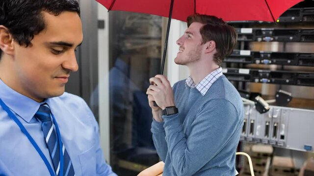 Animation of caucasian man with umbrella over biracial male worker inspecting server room