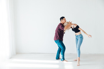 a woman and a man dancing to the music of a bachata in a white hall