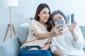 Asian lovely family, young daughter use phone selfie with older mother