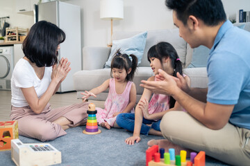 Asian happy family sit on floor, play kid toy together in living room. 