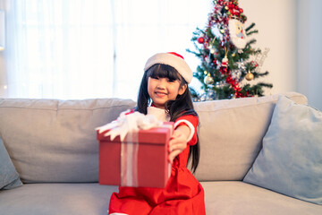 Portrait of Asian young girl kid wear Santa hat and hold X mas gift. 
