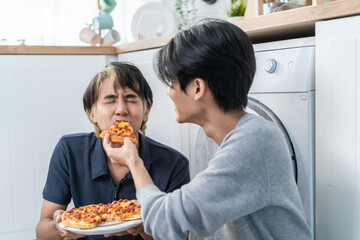 Asian handsome man gay family sitting on floor, eating pizza together. 