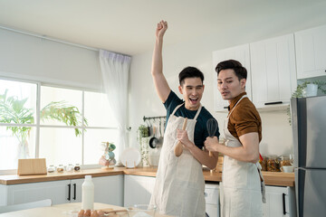 Asian happy handsome man gay couple sing and dance together in kitchen